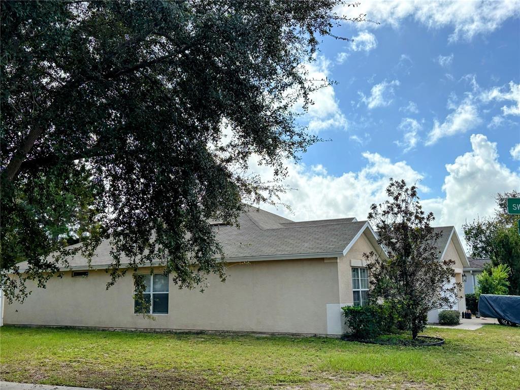 A side view of a beige single-story house with a shingled roof and large tree — 3921 SW 58TH AVENUE, OCALA, FL