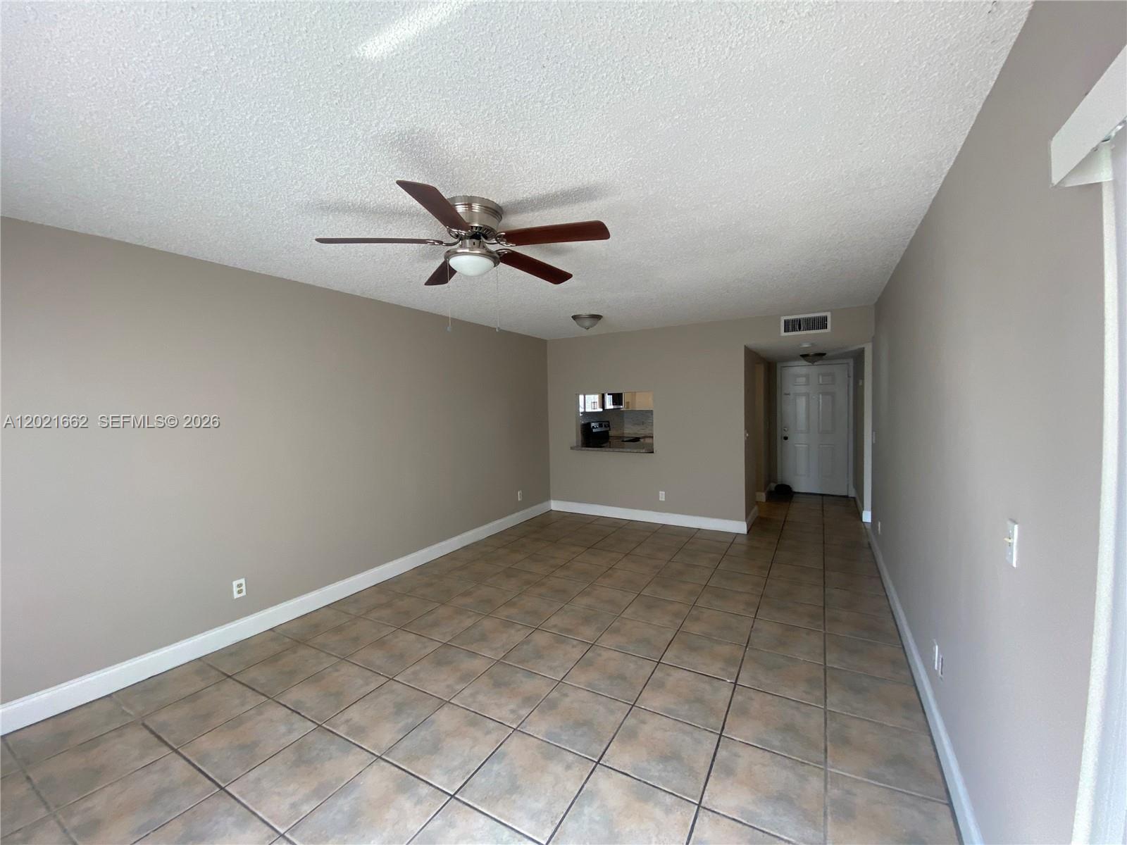 An empty living room features beige walls, a ceiling fan, and brown tiled flooring — 3263 Kirk Rd # 2, Lake Worth FL 33461, LAKE WORTH, FL