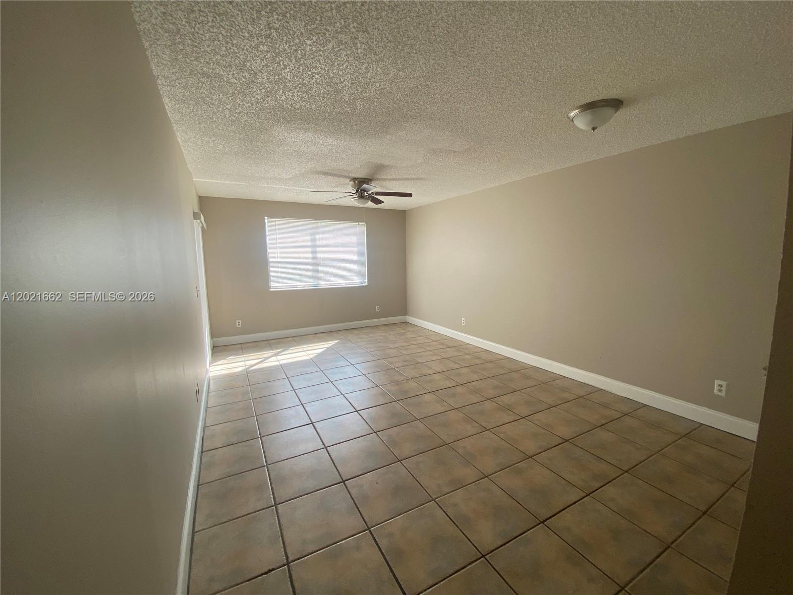 An empty room features beige walls, a tiled floor, a ceiling fan, and a window — 3263 Kirk Rd # 2, Lake Worth FL 33461, LAKE WORTH, FL