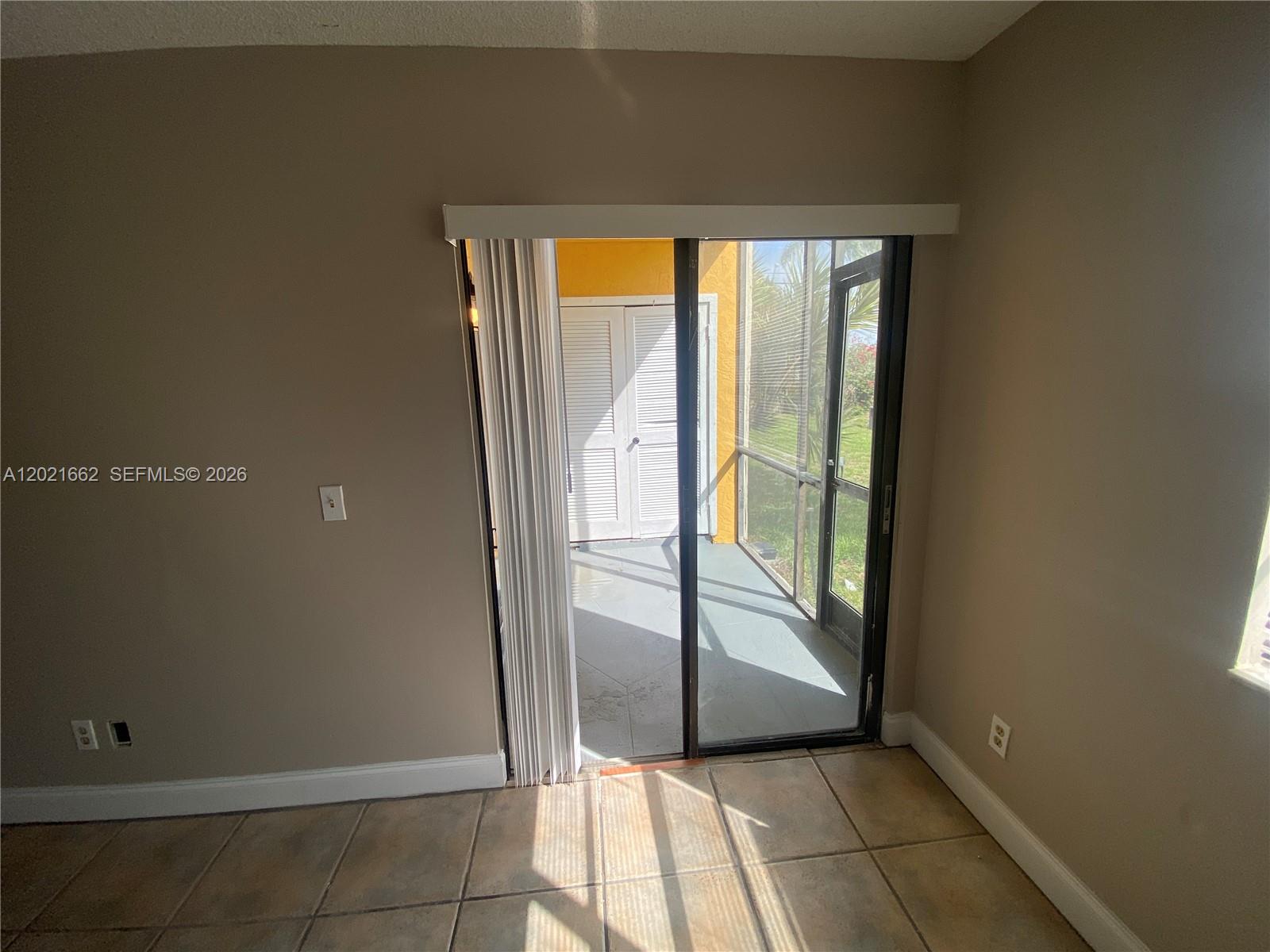 A room with tiled floors features a sliding glass door leading to a screened patio — 3263 Kirk Rd # 2, Lake Worth FL 33461, LAKE WORTH, FL