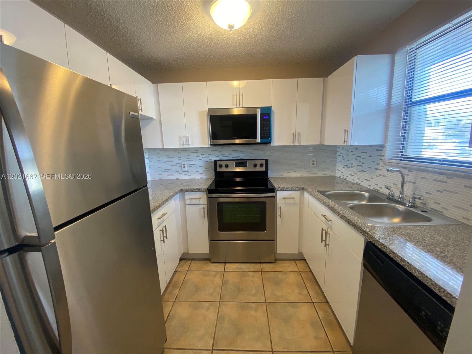 A kitchen features white cabinets, stainless steel appliances, granite countertops, and a tiled backsplash — 3263 Kirk Rd # 2, Lake Worth FL 33461, LAKE WORTH, FL