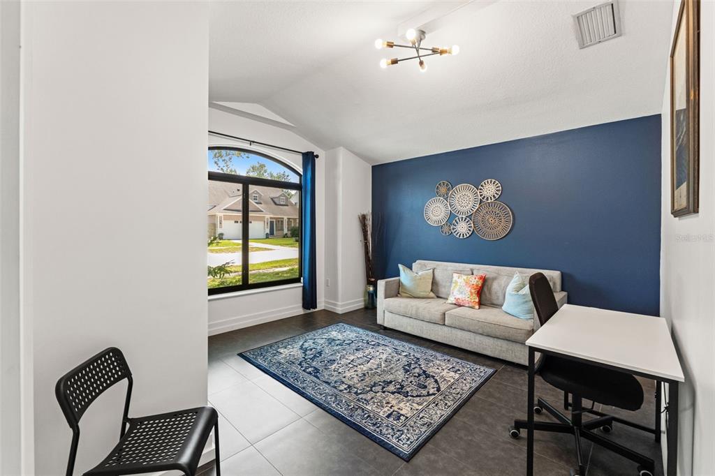 A room with a blue accent wall, a sofa, a desk, and a large arched window — 24405 SUMMER WIND COURT, LUTZ, FL