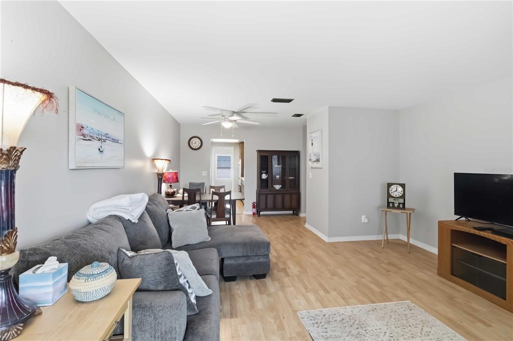 A living room features a gray sectional sofa, light wood flooring, and a television console — 6000 20TH STREET N UNIT 144, ST PETERSBURG, FL