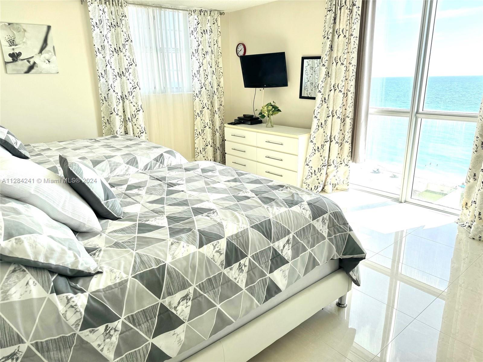 A bedroom with two beds, a dresser, and a large window overlooking the ocean — 3901 S Ocean Dr # 8E, Hollywood FL 33019, HOLLYWOOD, FL
