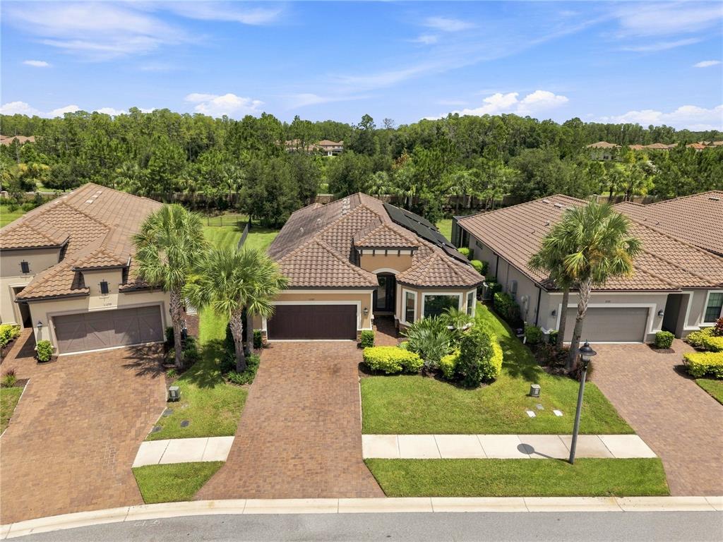An aerial view shows three suburban houses with tiled roofs and paved driveways — 11301 JUGLANS DRIVE, ODESSA, FL