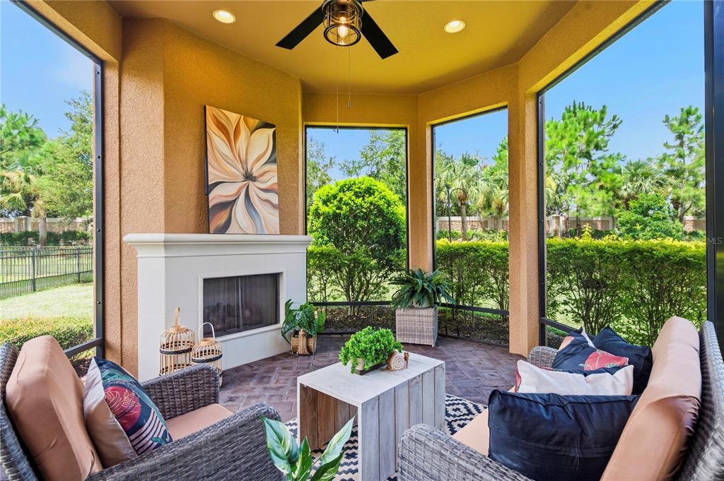 A screened-in patio features a fireplace, wicker furniture, and views of a landscaped backyard — 11301 JUGLANS DRIVE, ODESSA, FL
