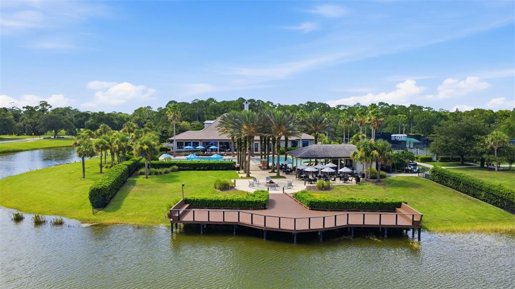 An aerial view shows a clubhouse with a pool, patio, and deck overlooking a lake — 38 TREETOP CIRCLE, ORMOND BEACH, FL