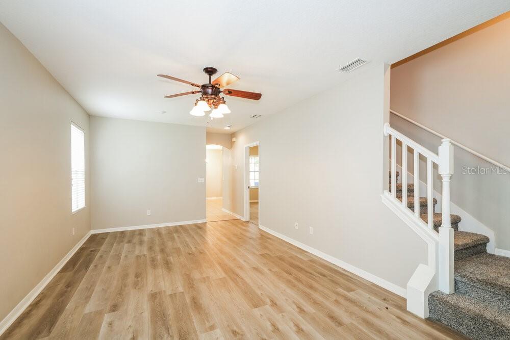 A living room with light wood flooring, a ceiling fan, and a staircase with railing — 16014 LONEOAK VIEW DRIVE, LITHIA, FL