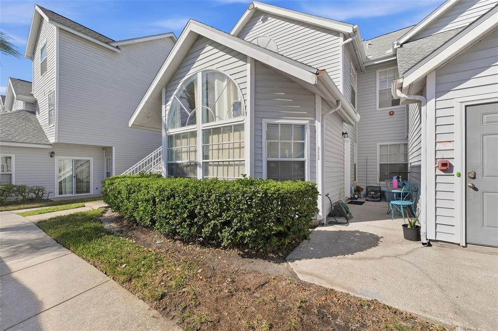 A light gray multi-story townhouse exterior features a large arched window and a concrete patio — 12245 ARMENIA GABLES CIRCLE UNIT 12245, TAMPA, FL