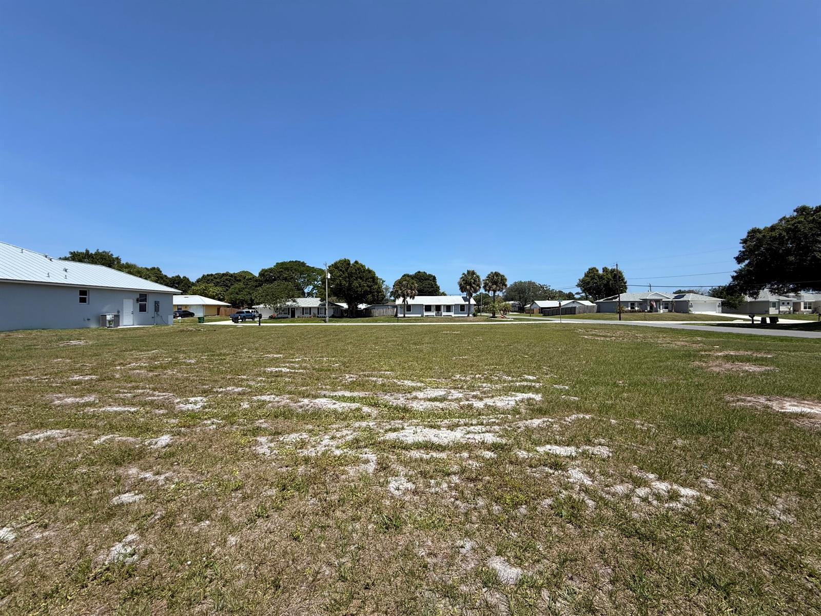 A large, grassy vacant residential lot sits in a suburban neighborhood under a clear sky — Tbd Seagrape Drive, Fort Pierce FL 34982, FORT PIERCE, FL