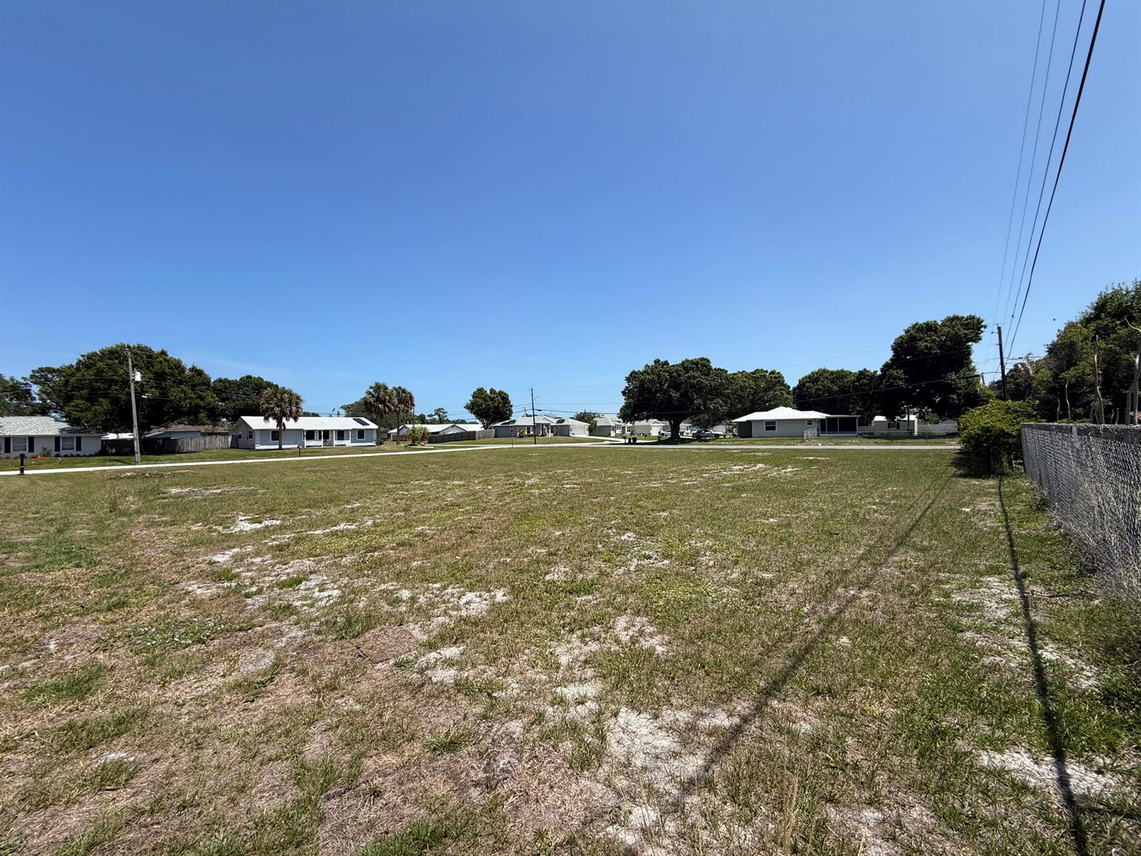 A large, flat, grassy vacant lot is surrounded by residential houses and a chain-link fence — Tbd Seagrape Drive, Fort Pierce FL 34982, FORT PIERCE, FL