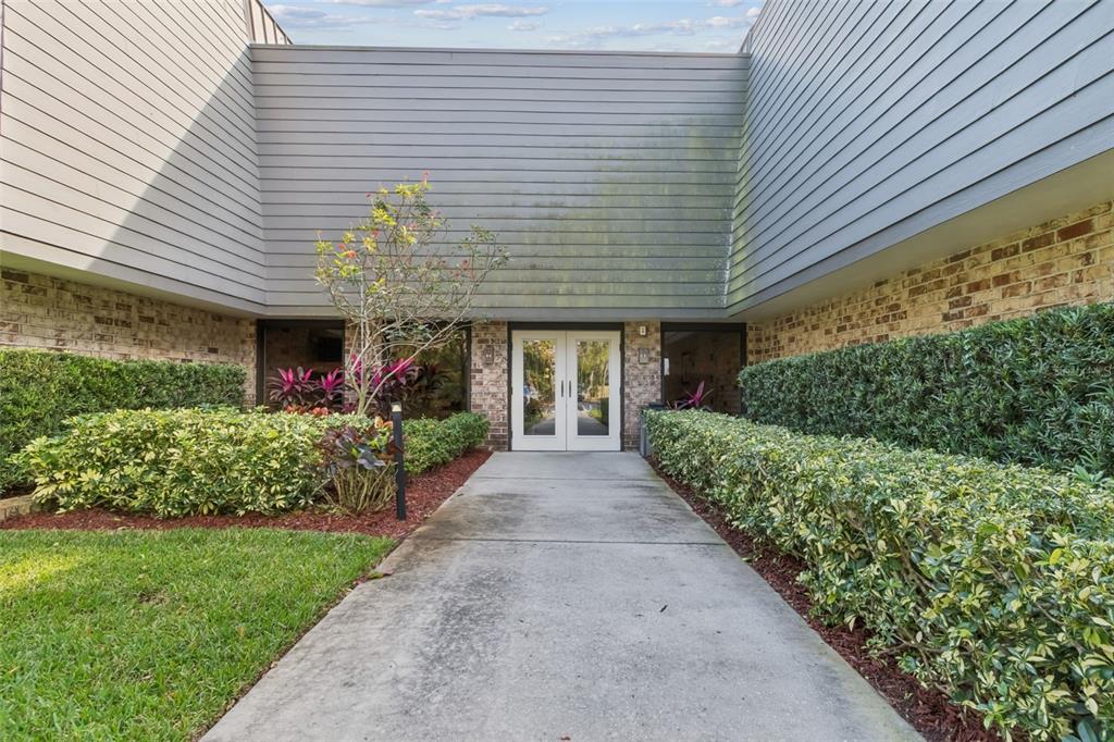 A concrete walkway leads to the double glass front doors of a two-story building — 36750 US HIGHWAY 19 N UNIT 17208, PALM HARBOR, FL