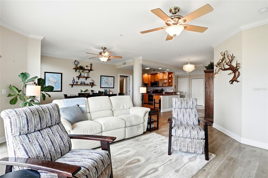 A living room features a white sofa, two patterned armchairs, and an open-concept kitchen — 750 4TH AVENUE S UNIT 705D, ST PETERSBURG, FL