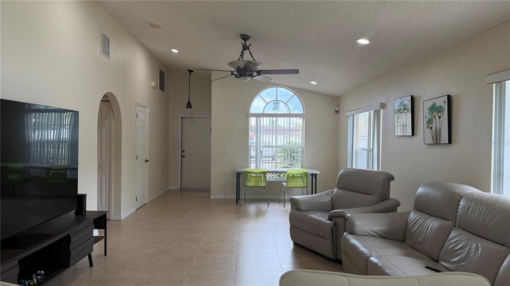 A living room with tile floors, a ceiling fan, a television, and leather seating — 632 DHARMA CIRCLE, WINTER GARDEN, FL