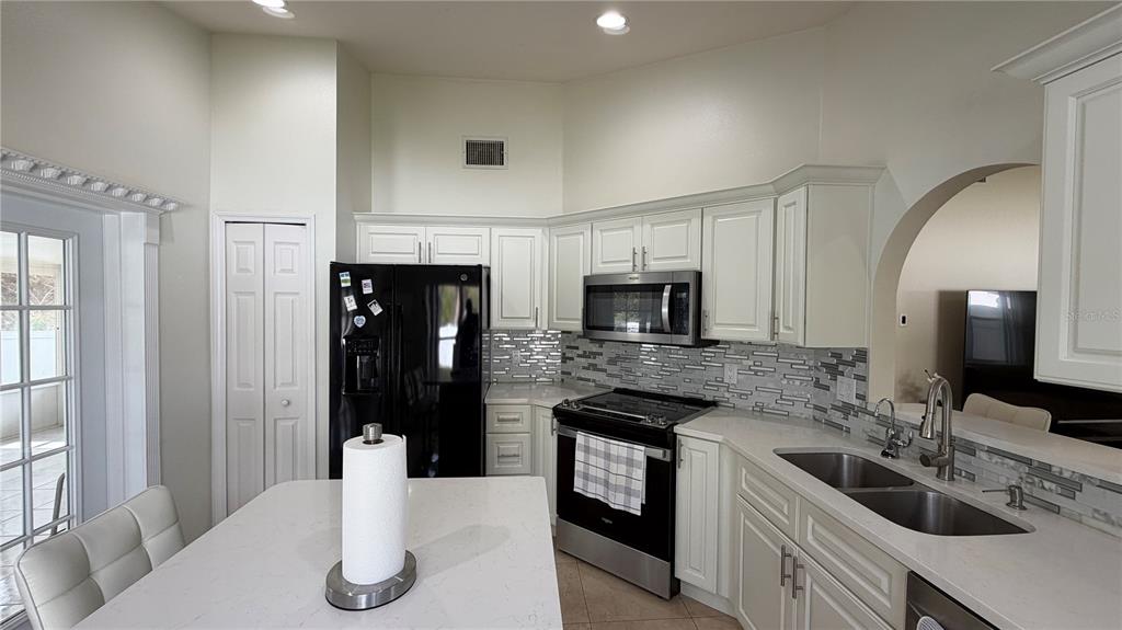 A kitchen features white cabinets, a black refrigerator, a stainless steel stove, and a countertop — 632 DHARMA CIRCLE, WINTER GARDEN, FL
