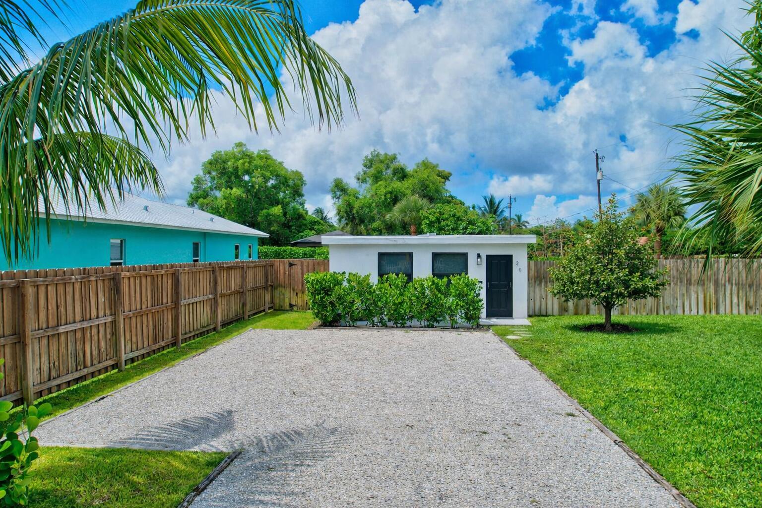 A white detached building sits at the end of a gravel driveway in a backyard — 201 SE 7th Street, Delray Beach FL 33483, DELRAY BEACH, FL