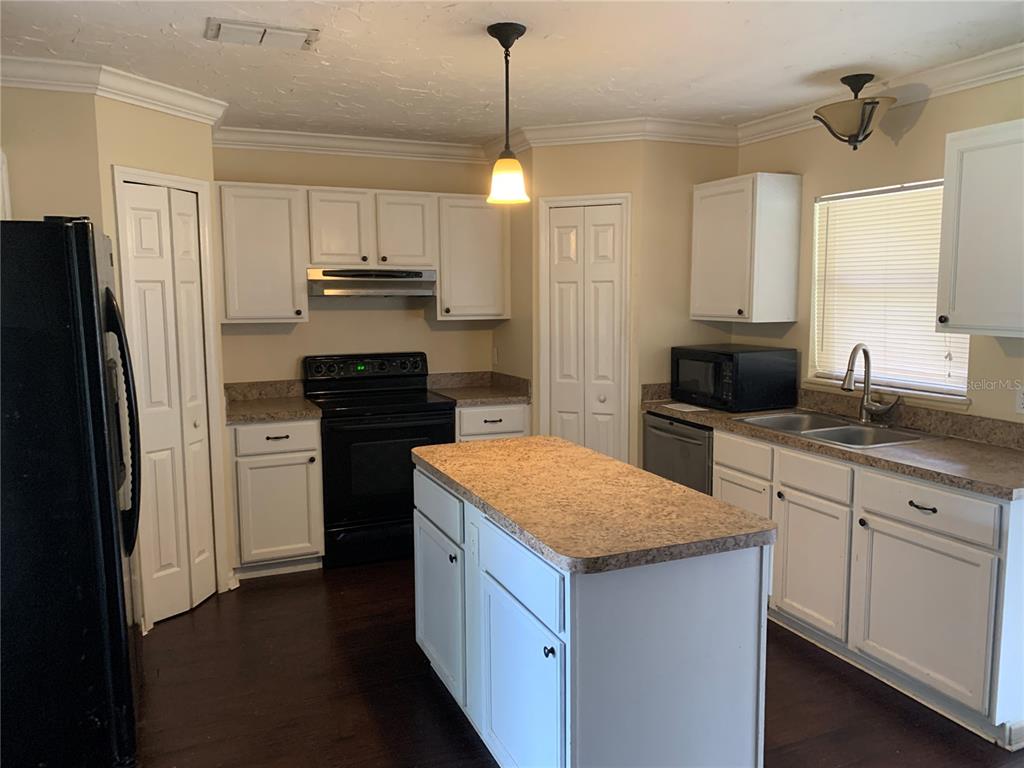 A kitchen features white cabinets, a central island, black appliances, and tan laminate countertops — 4300 IVEYGLEN AVENUE, ORLANDO, FL