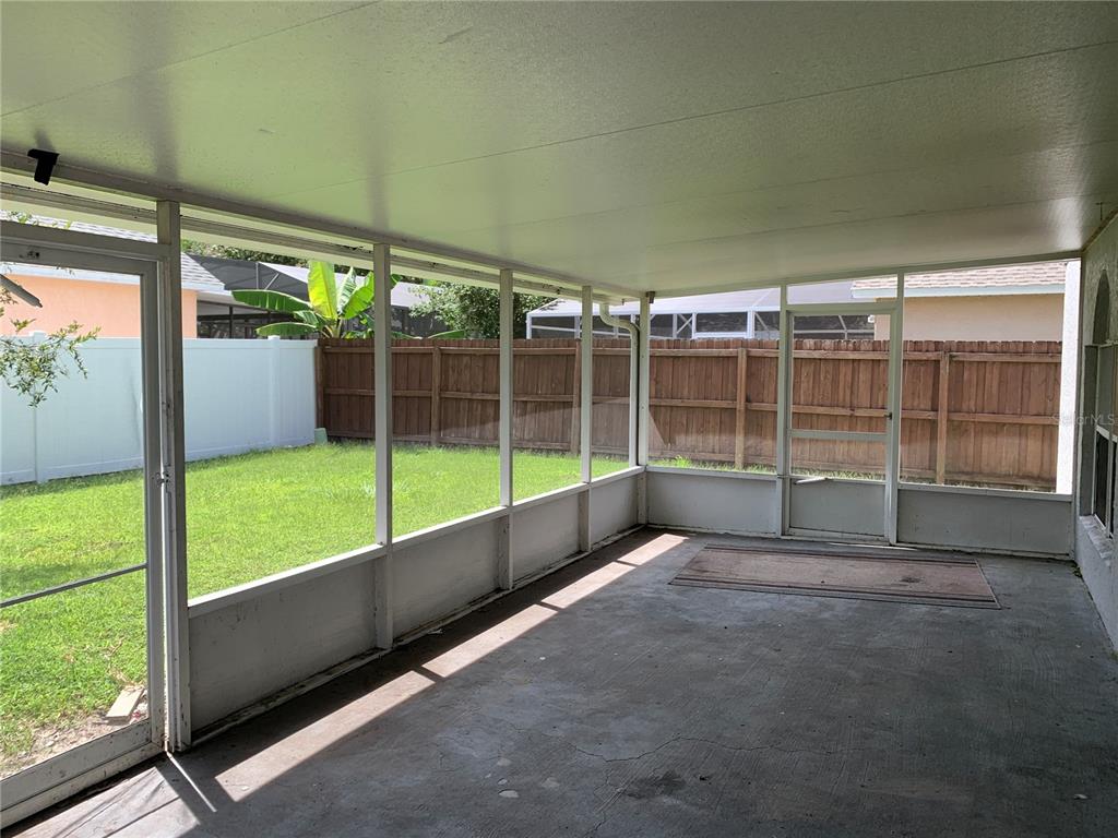 A screened-in porch with a concrete floor overlooks a fenced backyard — 4300 IVEYGLEN AVENUE, ORLANDO, FL