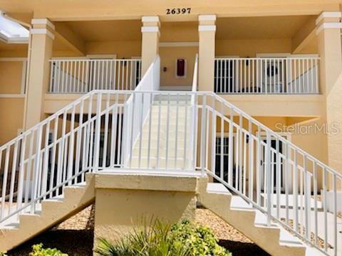 An exterior view of a two-story apartment building with white railings and concrete stairs — 26397 NADIR ROAD UNIT 204, PUNTA GORDA, FL