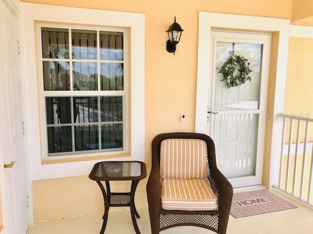A patio features a wicker chair, a small side table, a window, and a door — 26397 NADIR ROAD UNIT 204, PUNTA GORDA, FL
