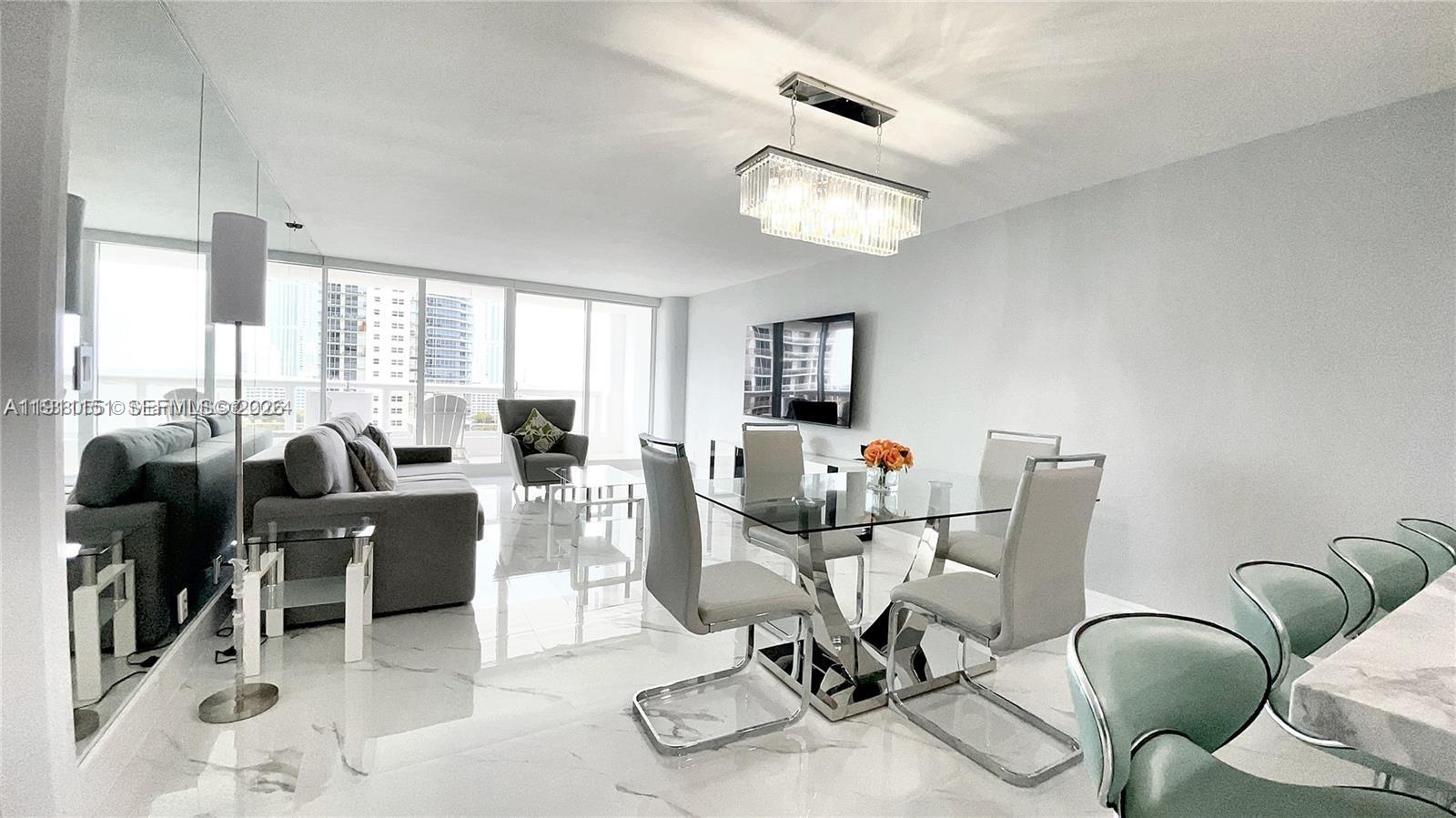 A modern living and dining area features white marble floors, a glass table, and balcony views — 1717 N Bayshore Dr # 1950, Miami FL 33132, MIAMI, FL