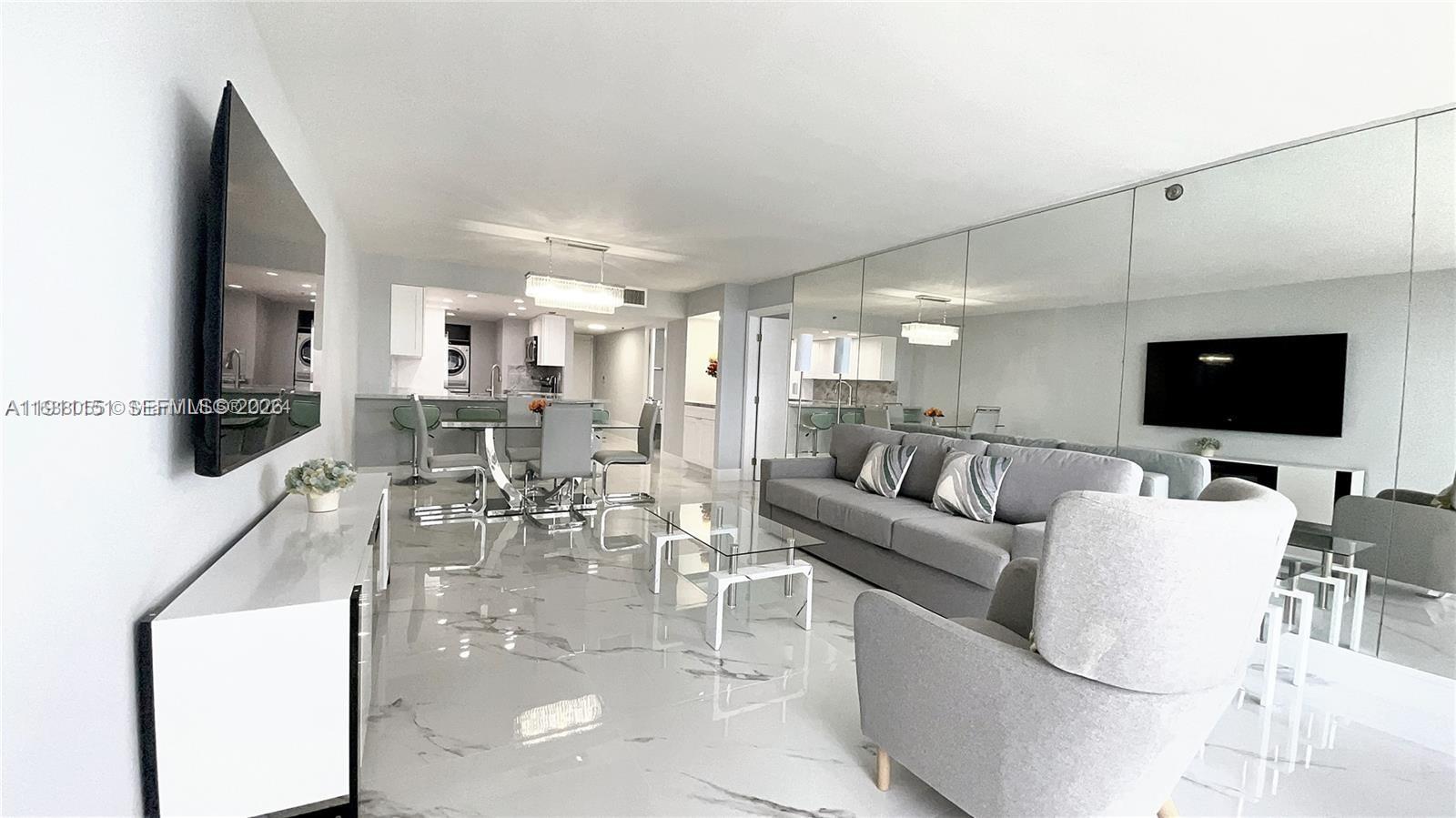 A modern living room features marble floors, a grey sofa, and a mirrored wall — 1717 N Bayshore Dr # 1950, Miami FL 33132, MIAMI, FL