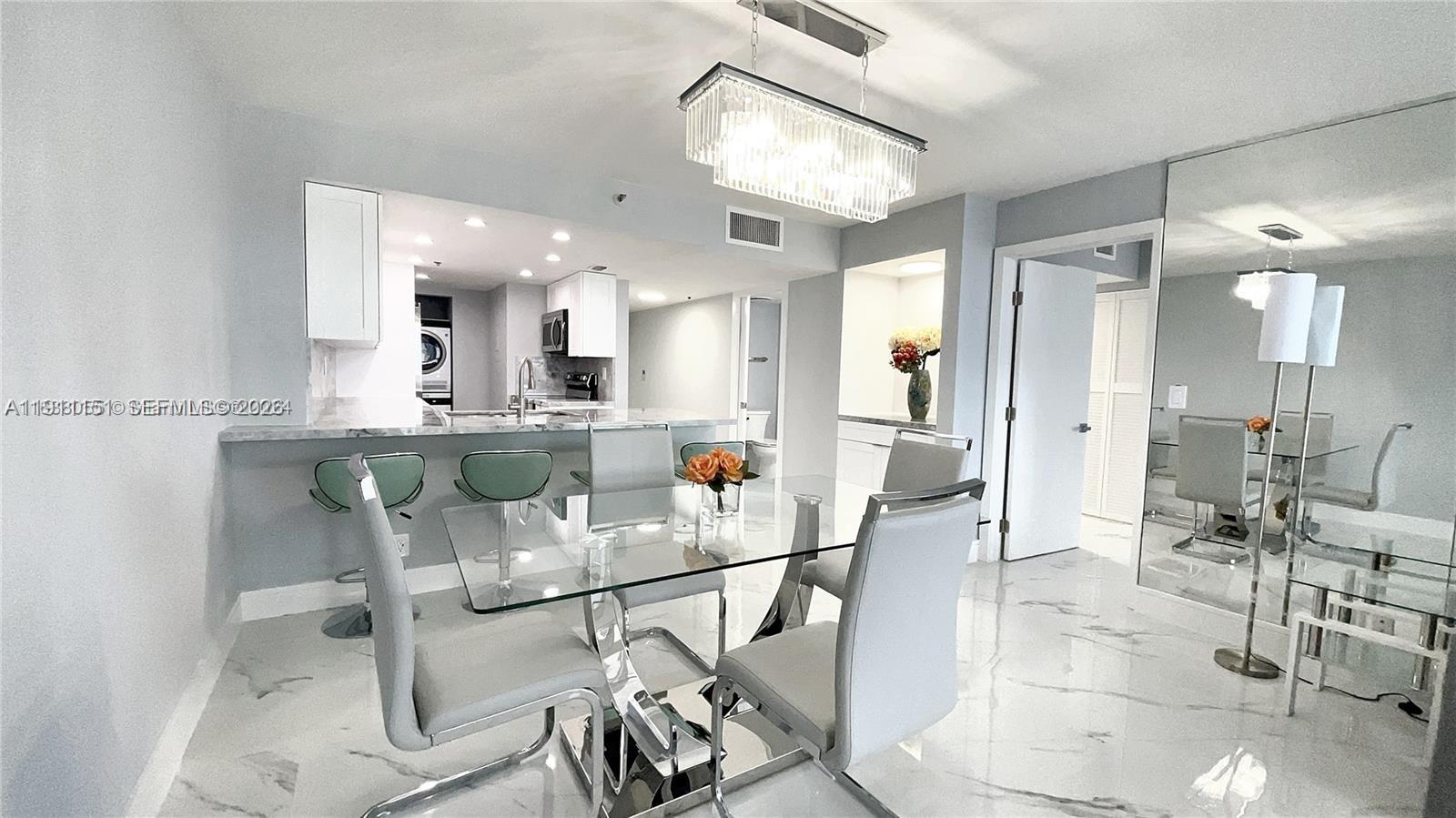 A dining area with a glass table, modern chairs, and a crystal chandelier — 1717 N Bayshore Dr # 1950, Miami FL 33132, MIAMI, FL