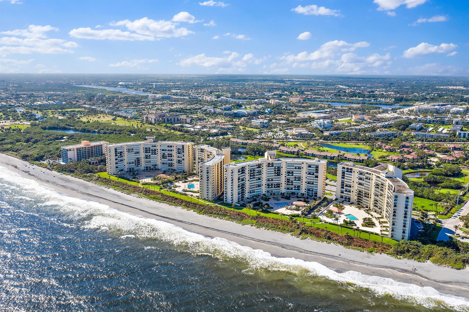 An aerial view of several multi-story beachfront condominium buildings along a sandy coastline — 300 Ocean Trail Way # 403, Jupiter FL 33477, JUPITER, FL
