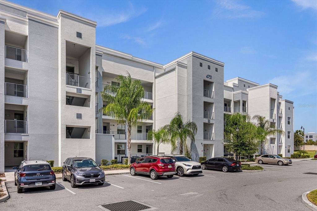 A multi-story apartment building with a parking lot in front under a sunset sky — 4751 CLOCK TOWER DRIVE UNIT 204, KISSIMMEE, FL