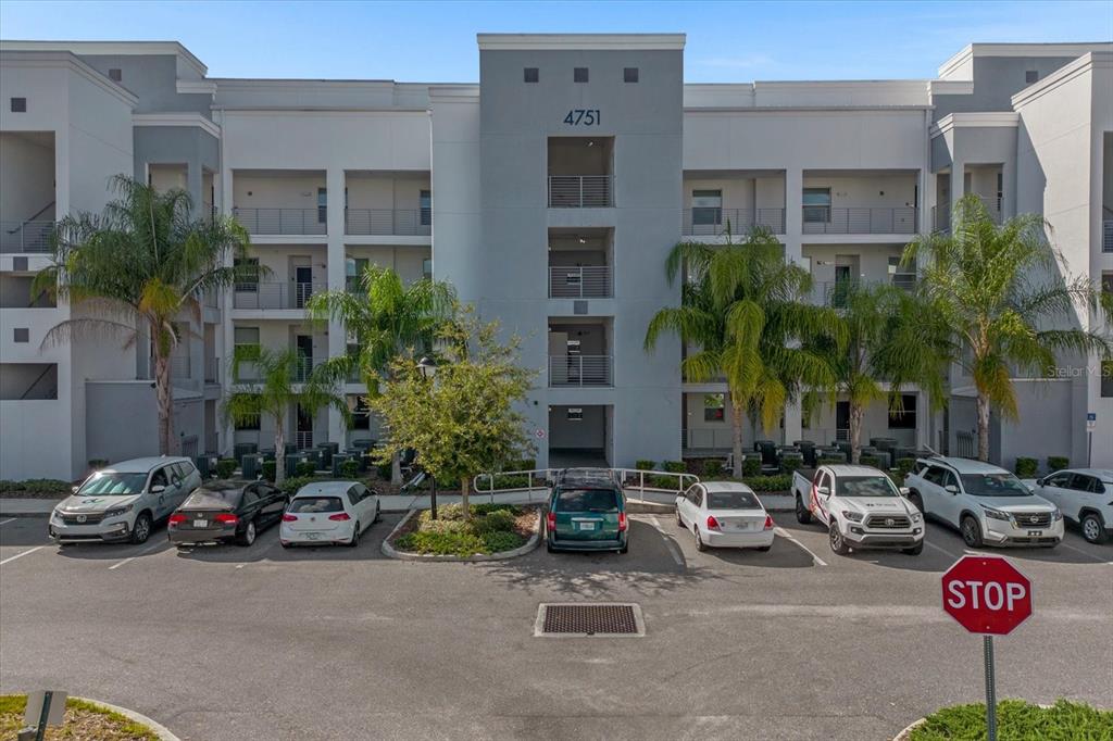 A multi-story apartment building with a parking lot in front under a blue sky — 4751 CLOCK TOWER DRIVE UNIT 204, KISSIMMEE, FL