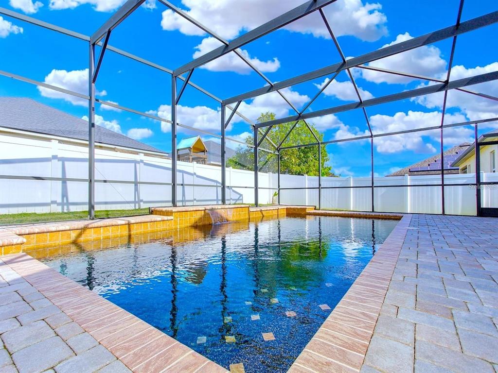 A swimming pool with a water feature inside a screened-in patio enclosure — 4461 INDIGO SKY LANE, KISSIMMEE, FL