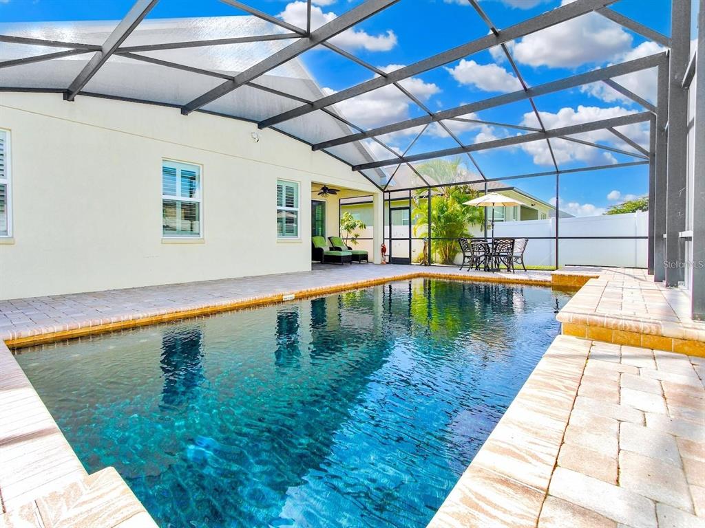 A swimming pool with a stone deck is enclosed by a screened lanai — 4461 INDIGO SKY LANE, KISSIMMEE, FL