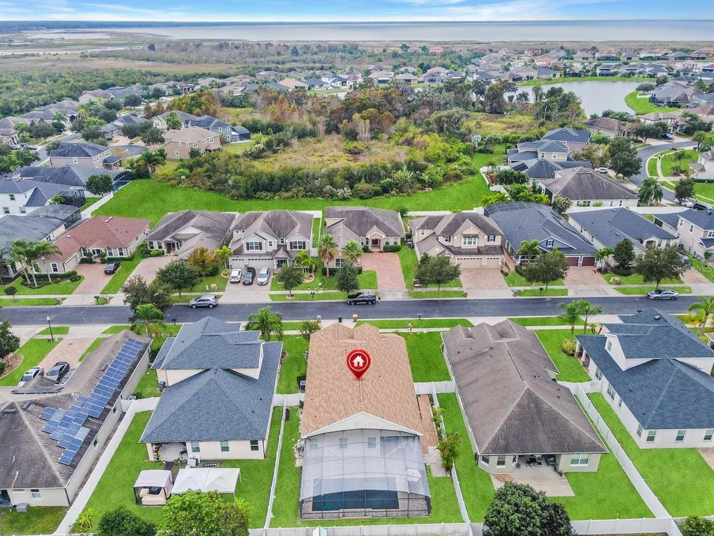 An aerial view shows a residential neighborhood with a house featuring a screened-in pool — 4461 INDIGO SKY LANE, KISSIMMEE, FL