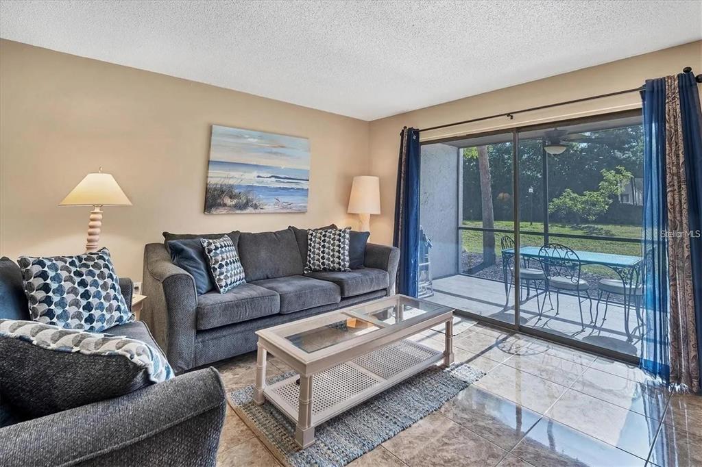 A living room features a gray sofa, a glass-top coffee table, and a sliding glass door — 1624 STICKNEY POINT ROAD UNIT 108, SARASOTA, FL