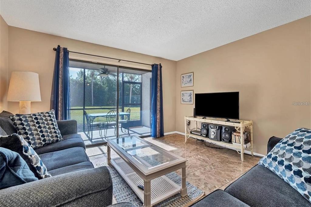 A living room features tile floors, a glass coffee table, and a sliding door to a patio — 1624 STICKNEY POINT ROAD UNIT 108, SARASOTA, FL