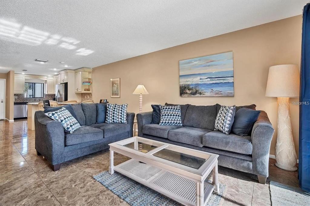 A living room features two gray sofas, a glass-top coffee table, and tiled flooring — 1624 STICKNEY POINT ROAD UNIT 108, SARASOTA, FL