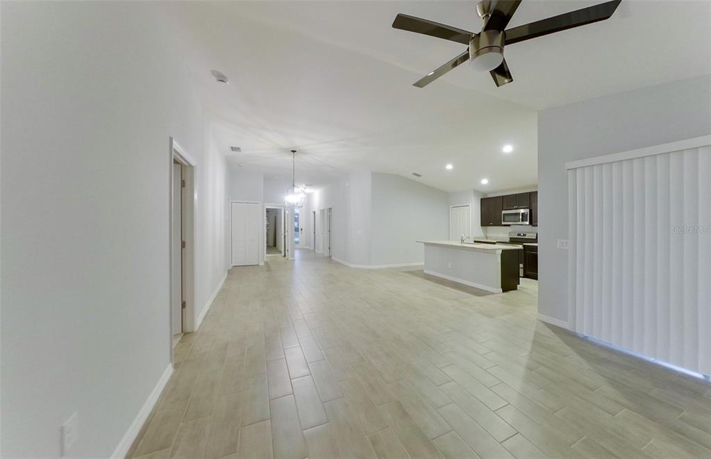 An open-concept living area features light-colored tile flooring, a kitchen island, and a ceiling fan — 227 PENNFIELD STREET, LEHIGH ACRES, FL
