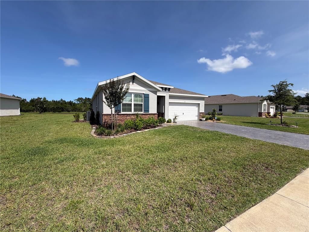 A single-story suburban house with a stone facade, white garage, and a paved driveway — 85 HUNTINGTON PLACE, ORMOND BEACH, FL