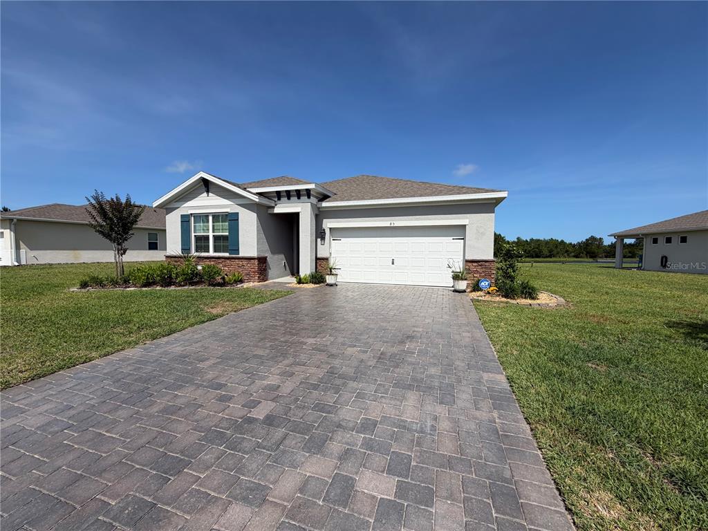 A single-story house features a paved driveway, a two-car garage, and stone veneer accents — 85 HUNTINGTON PLACE, ORMOND BEACH, FL