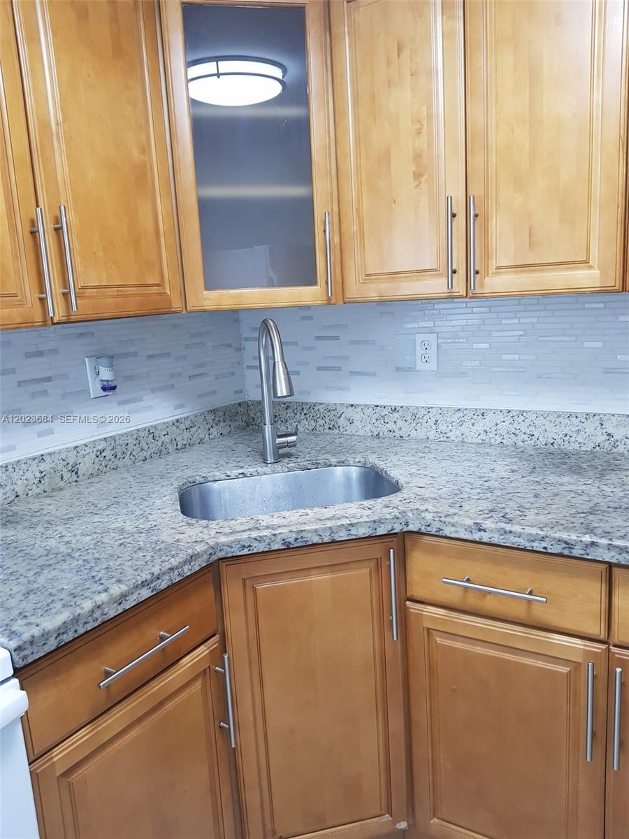 A kitchen features light wood cabinets, a granite countertop, and a stainless steel sink — 606 W 81st St # 314, Hialeah FL 33014, HIALEAH, FL