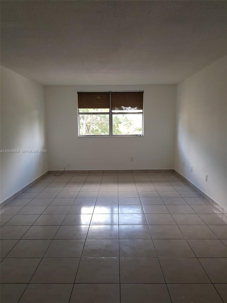 An empty room features white walls, light-colored floor tiles, and a single window with blinds — 606 W 81st St # 314, Hialeah FL 33014, HIALEAH, FL