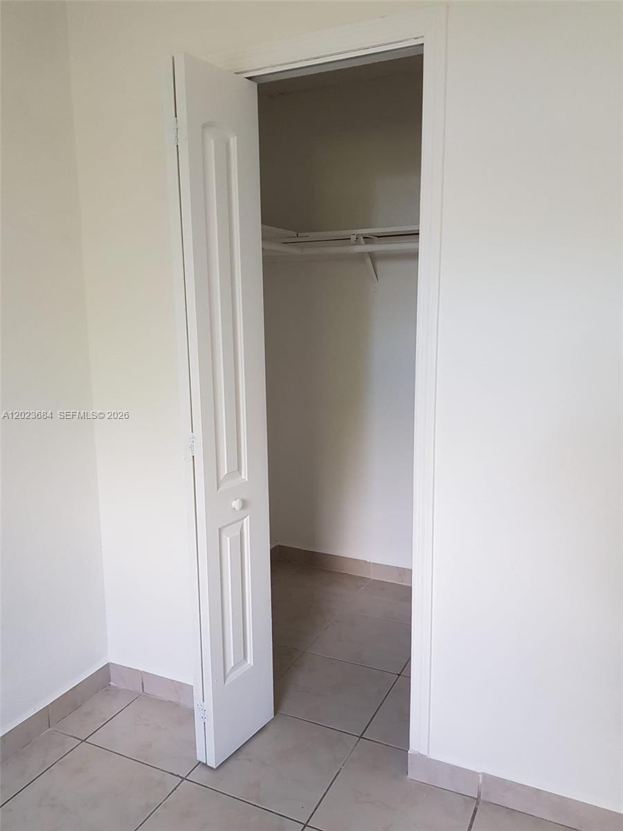 A closet with a white door, a shelf, and a rod sits in a tiled room — 606 W 81st St # 314, Hialeah FL 33014, HIALEAH, FL