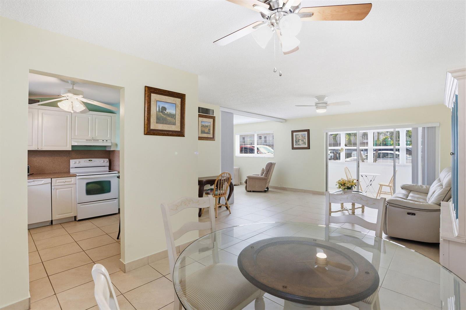 A bright, open-concept living and dining area features tile flooring, white cabinetry, and sliding doors — 721 Lori Drive # 113, Palm Springs FL 33461, PALM SPRINGS, FL