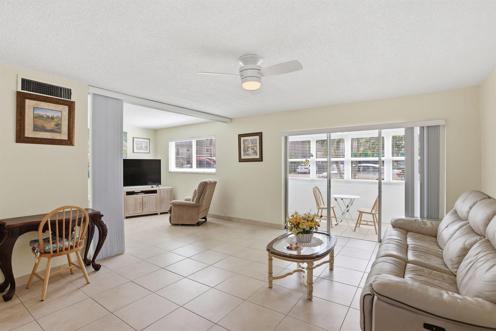 A living room with tile floors, a ceiling fan, and a sliding door to a balcony — 721 Lori Drive # 113, Palm Springs FL 33461, PALM SPRINGS, FL