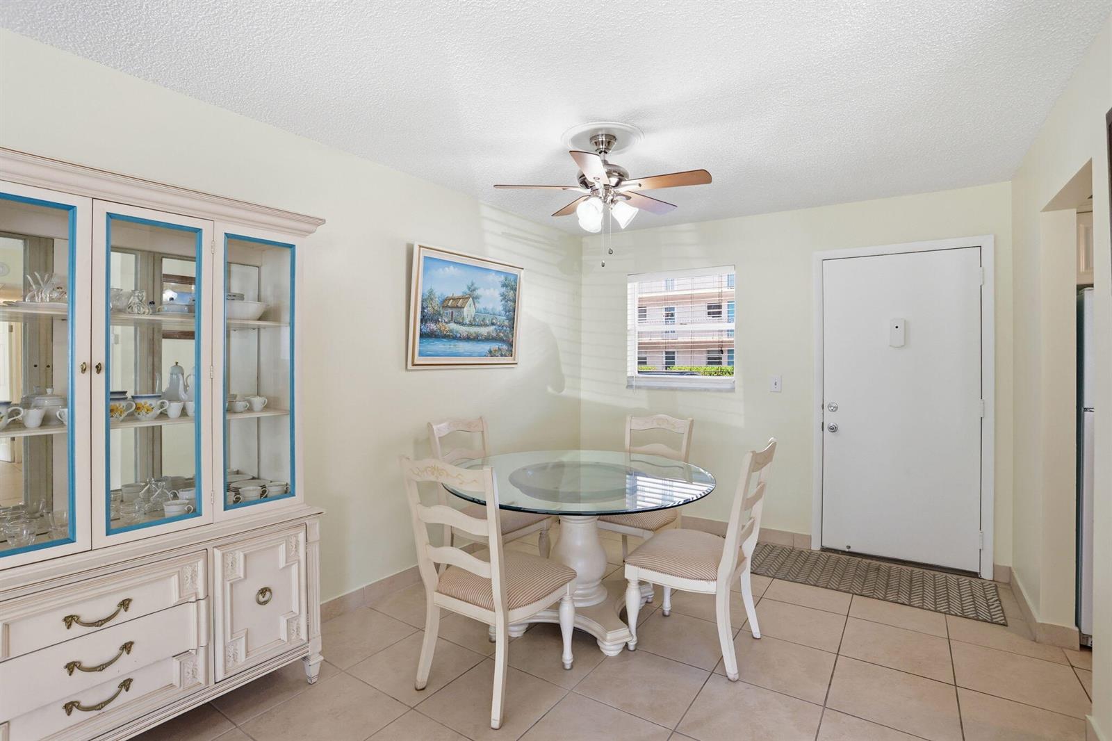 A dining area features a glass-topped table, four chairs, a china cabinet, and tile flooring — 721 Lori Drive # 113, Palm Springs FL 33461, PALM SPRINGS, FL