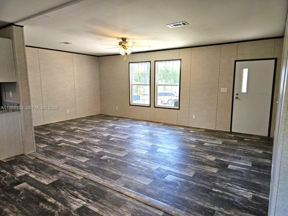 An empty room features light-colored paneled walls, a dark wood-look floor, and a ceiling fan — 881 Woodland Blvd, Clewiston FL 33440, CLEWISTON, FL