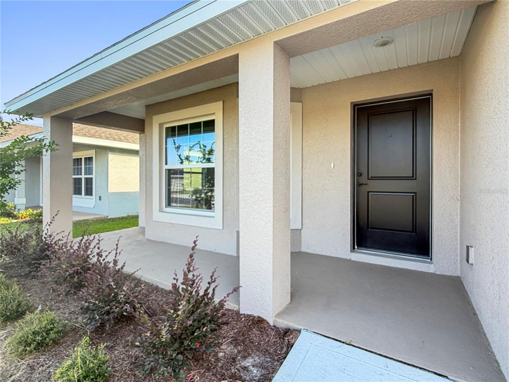 A covered front porch leads to a dark front door next to a single window — 7584 BENT TREE LOOP, ST CLOUD, FL