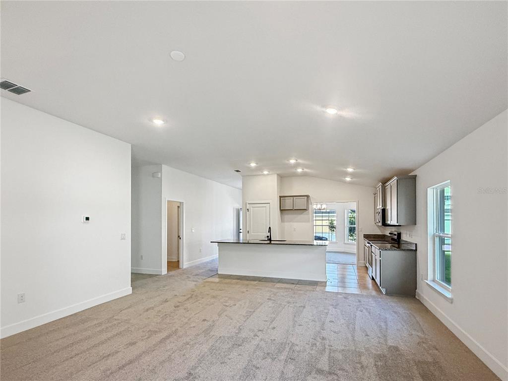 A carpeted living area opens to a kitchen with a central island and gray cabinets — 7584 BENT TREE LOOP, ST CLOUD, FL