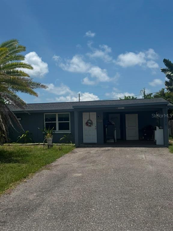 A single-story gray house features a front-facing carport and a paved driveway — 8271 PELICAN ROAD, ENGLEWOOD, FL