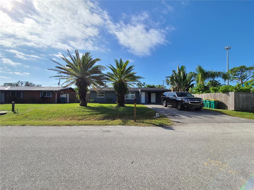 A single-story house with a gray exterior, two palm trees, and a driveway with a vehicle — 8271 PELICAN ROAD, ENGLEWOOD, FL